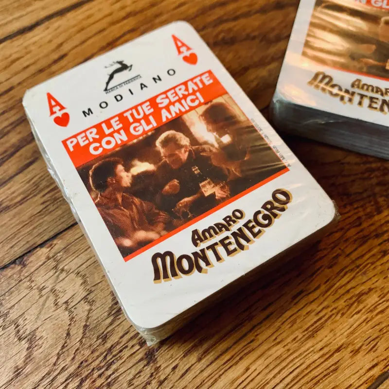 Carta da gioco raffigurante una pubblicità del liquore Amaro Montenegro con l’immagine di un gruppo sulla faccia.