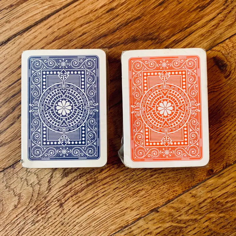 Due mazzi di carte da gioco, uno blu e uno arancione, con dorso decorato.