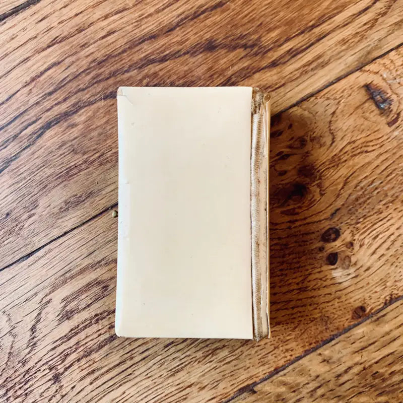 Libro o diario con copertina rigida color crema su una superficie di legno.