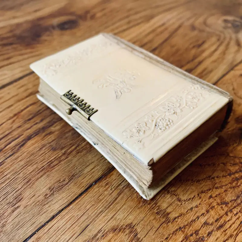 Libro bianco con copertina ornata e rilegatura a spirale su una superficie di legno.