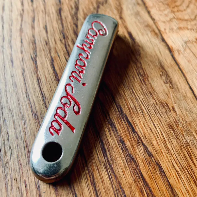 Apribottiglie metallico con incisione ’Barcardi Cola’ in caratteri rossi.