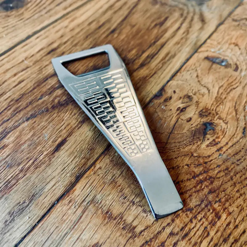 Apribottiglie in metallo con marchio ’Bitburger’ inciso sulla superficie.