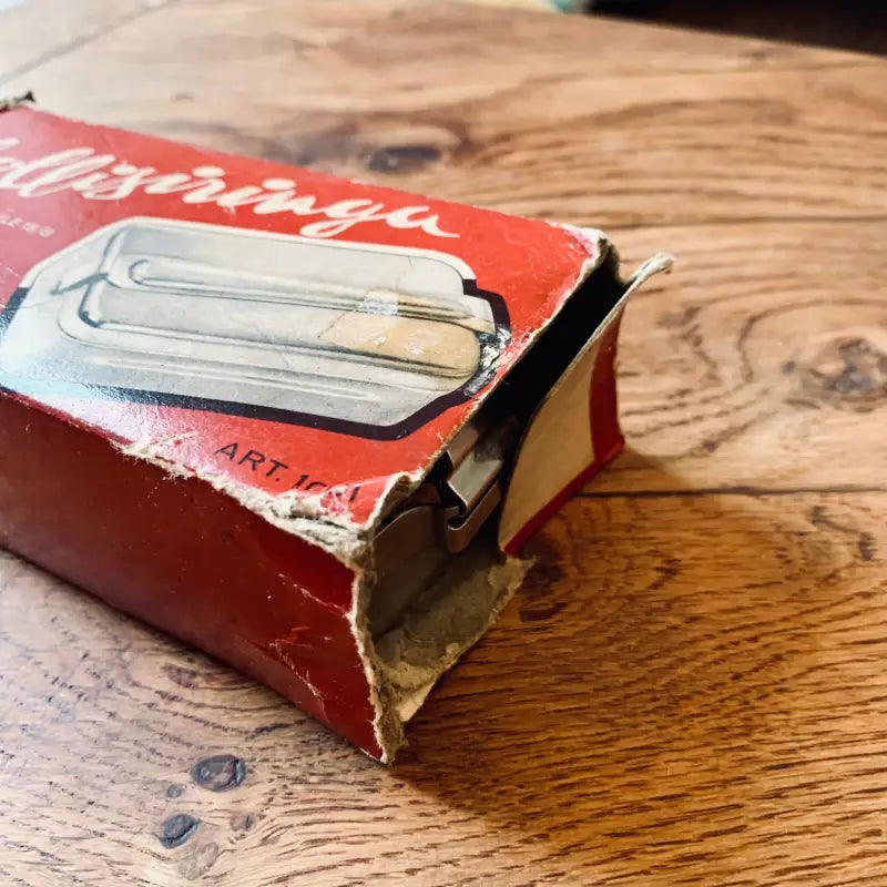 Libro o manuale rosso usurato con l’illustrazione di un apriscatole in metallo sulla copertina.