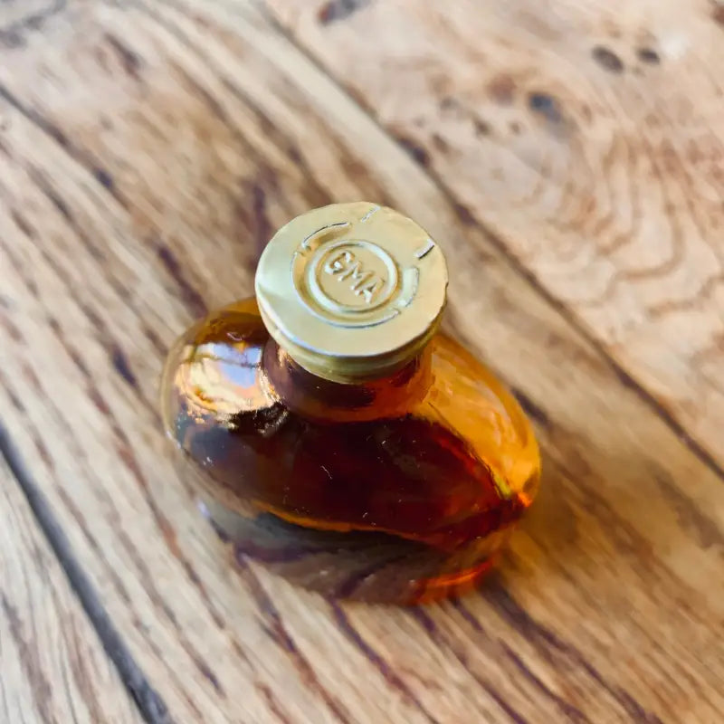 Piccola bottiglia di vetro contenente liquido ambrato con tappo dorato.