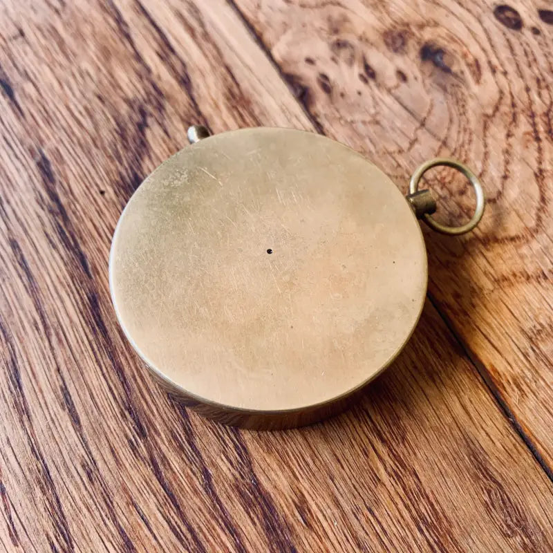 Ciondolo circolare in ottone o color oro con un piccolo occhiello per il fissaggio.