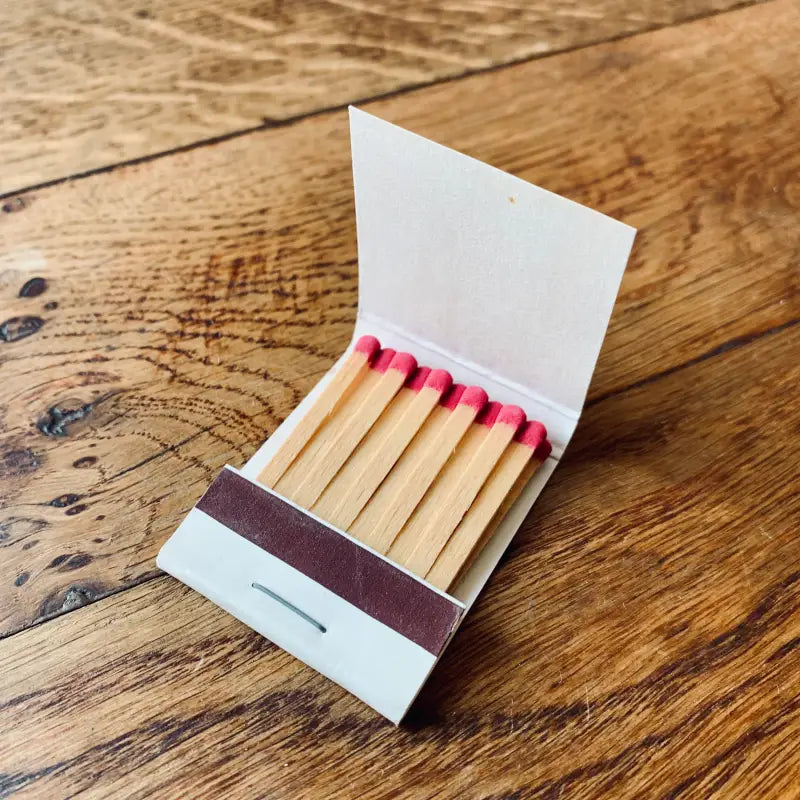 Libro di fiammiferi aperto contenente fiammiferi di legno con punte rosa.