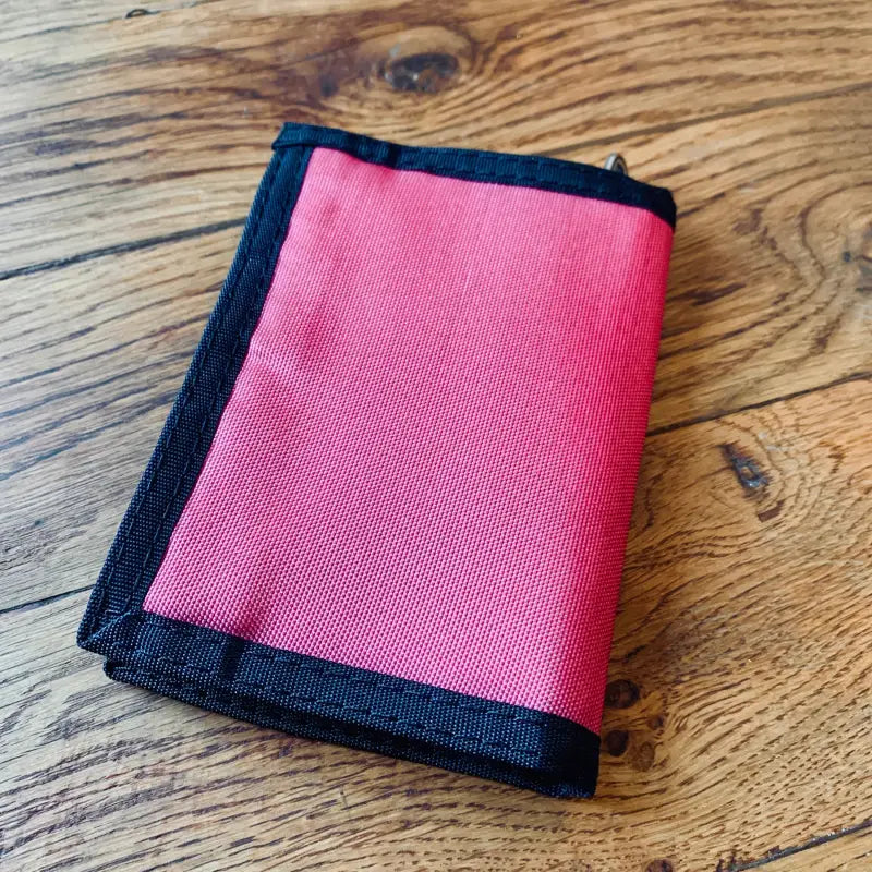 Portafoglio in tessuto rosso con finiture nere.