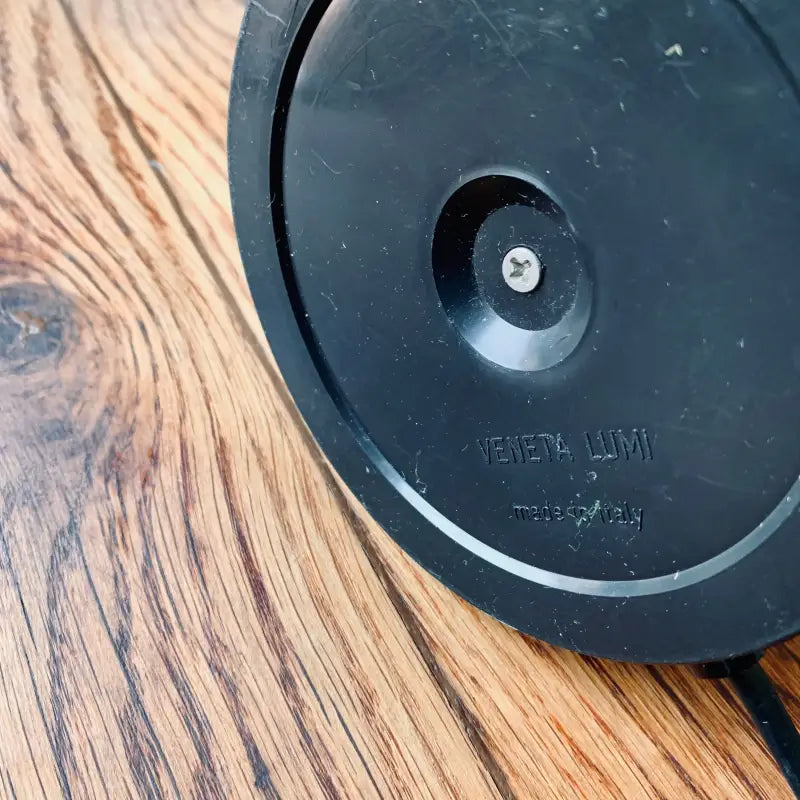 Diffusore circolare nero o dispositivo audio su una superficie di legno.