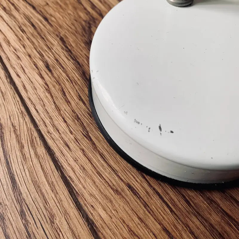 Aspirapolvere robotico parzialmente visibile su un pavimento in legno.
