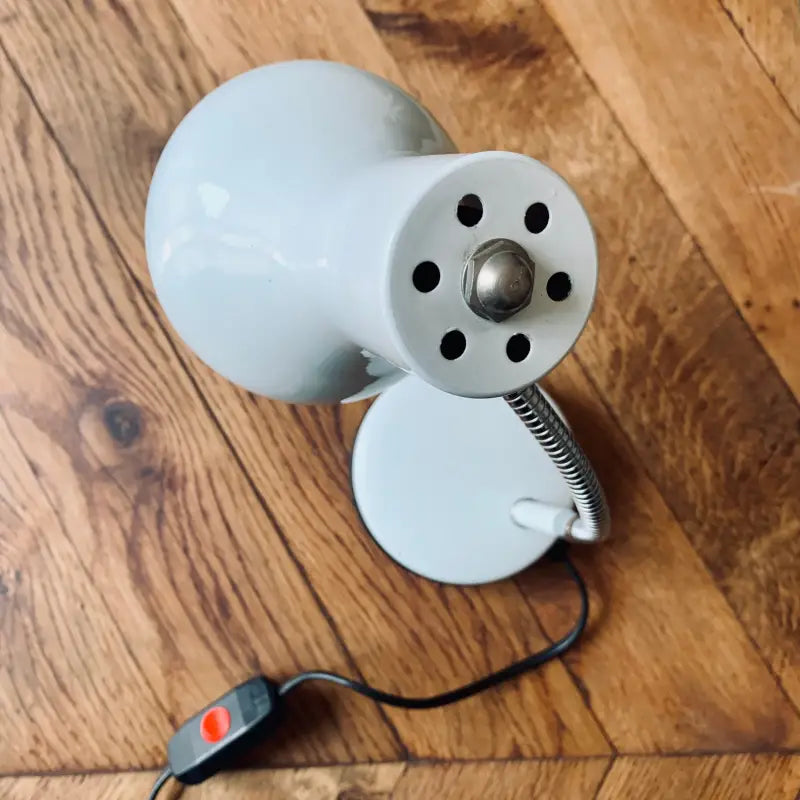Lampada da tavolo blu chiaro con base sferica e testa regolabile.