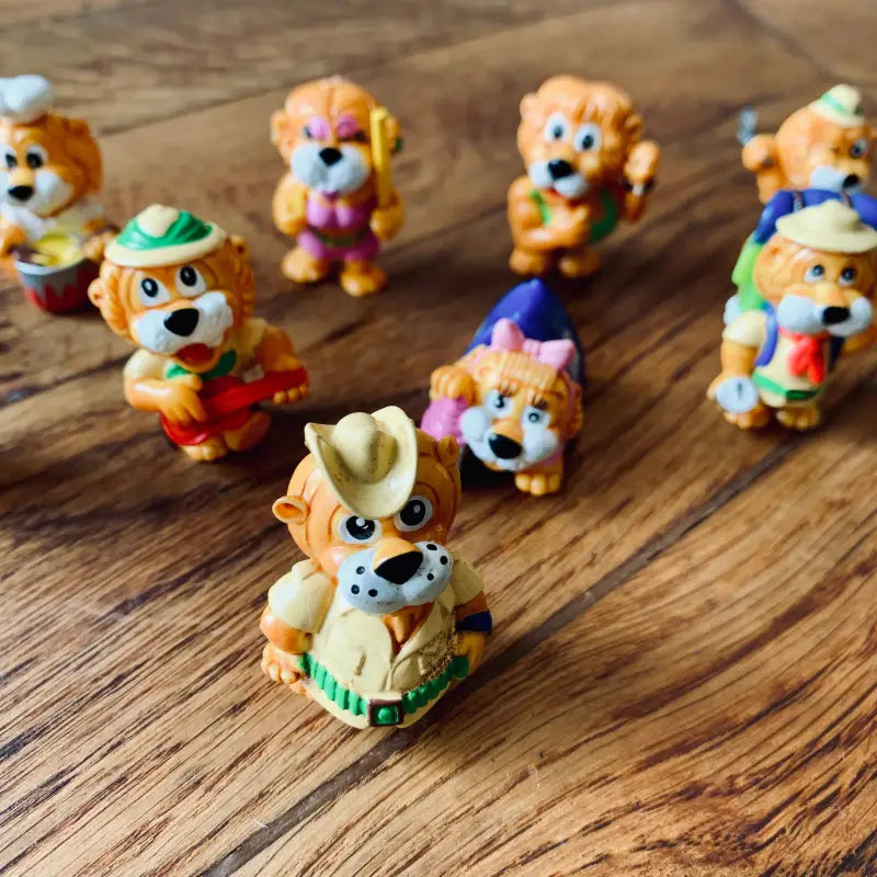 Collezione di figurine di animali colorati dei cartoni animati disposte su una superficie di legno.