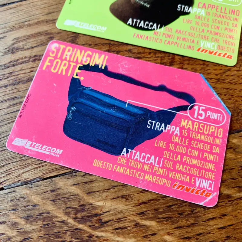 Biglietto telefonico rosa acceso con immagine di un marsupio blu.