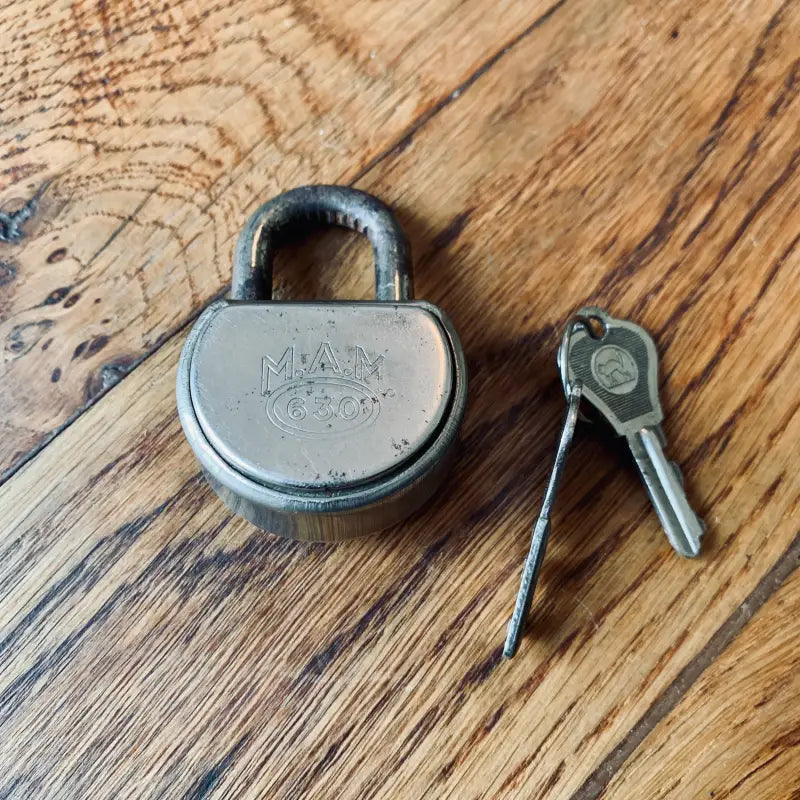 Lucchetto in metallo con incisione ’MAX’ sulla faccia, accompagnato dalla chiave.