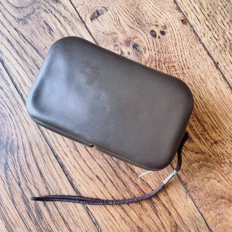 Astuccio o custodia in pelle nera con cerniera e cinturino da polso.