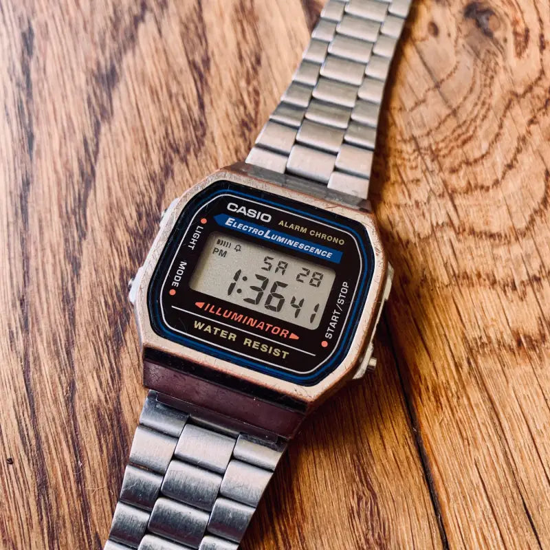 Orologio digitale Casio in stile vintage con cinturino in metallo su una superficie in legno.