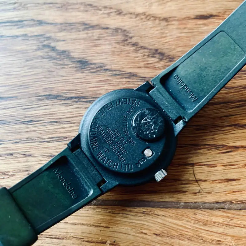 Orologio da polso nero con cinturino in pelle su una superficie in legno.