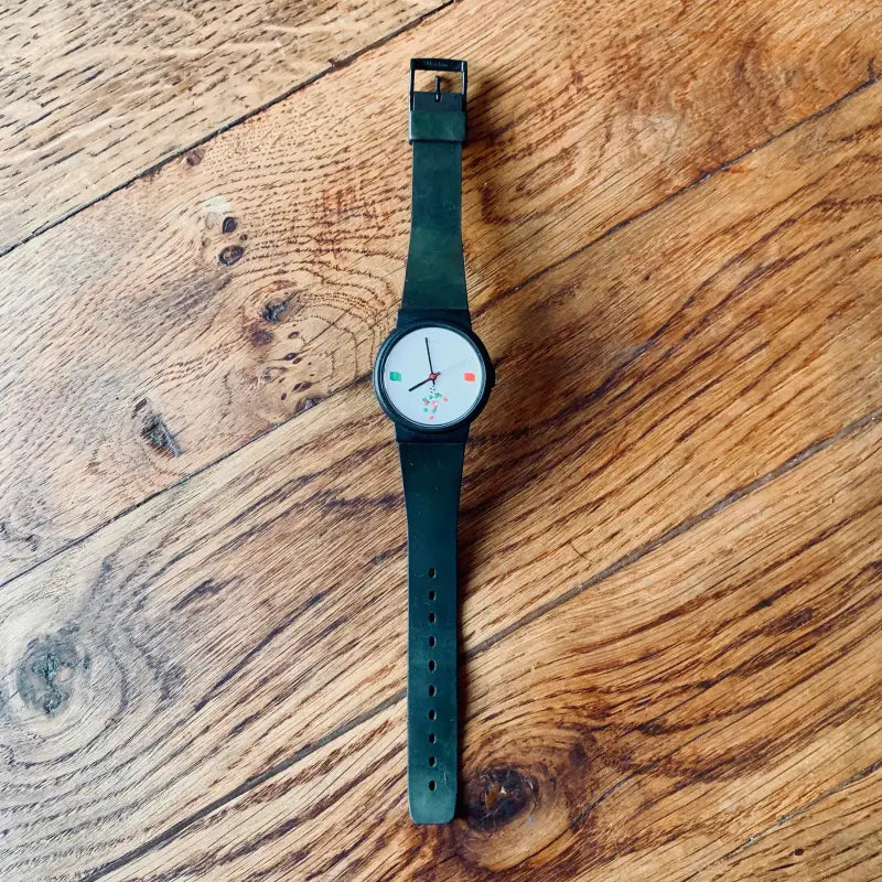 Orologio da polso con cinturino verde scuro e quadrante bianco minimalista.