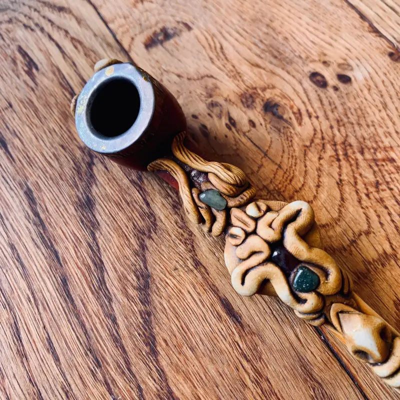 Pipa in legno ornata con intricati intagli e pietre intarsiate.