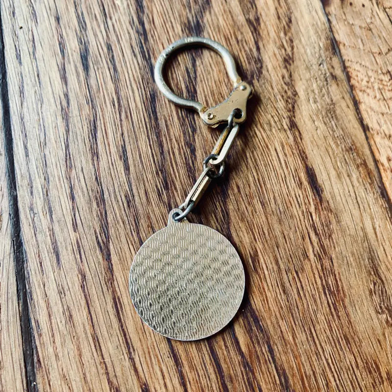Portachiavi in metallo con un ciondolo circolare a forma di texture.