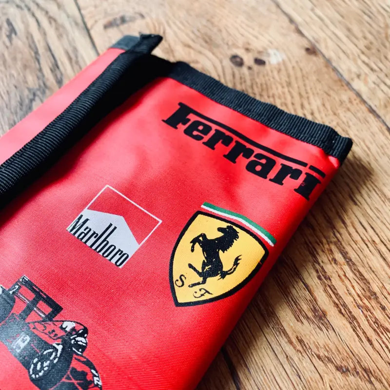 Borsa o sacchetto rosso a marchio Ferrari con i loghi Marlboro e Ferrari visibili.