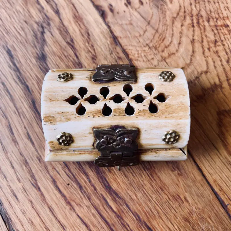 Scatola decorativa in legno con motivi floreali intagliati e accenti metallici.