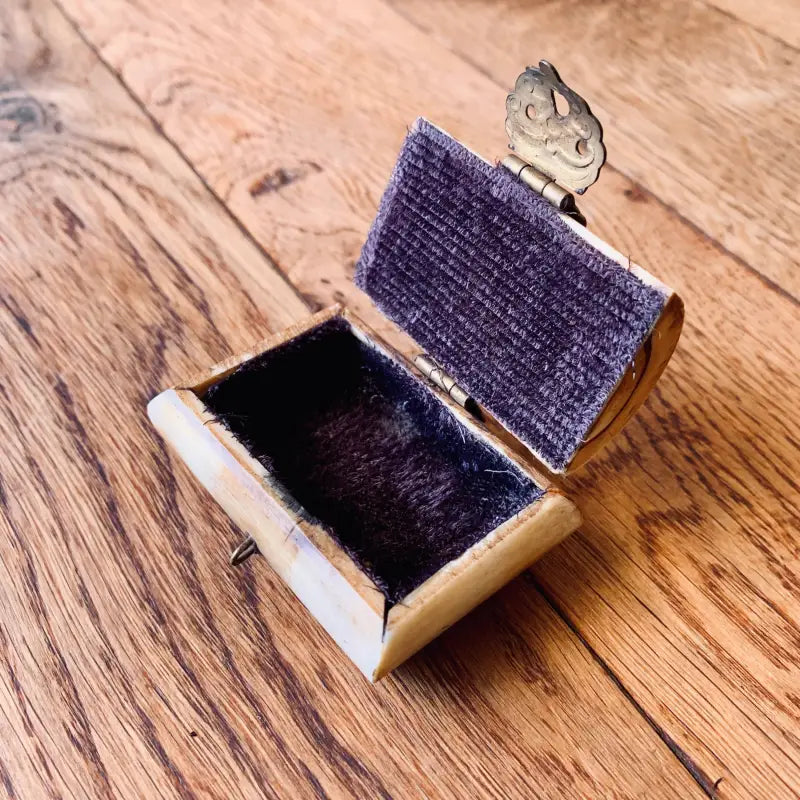 Miniatura di un divano di velluto viola con un piccolo topo che fa capolino da dietro.