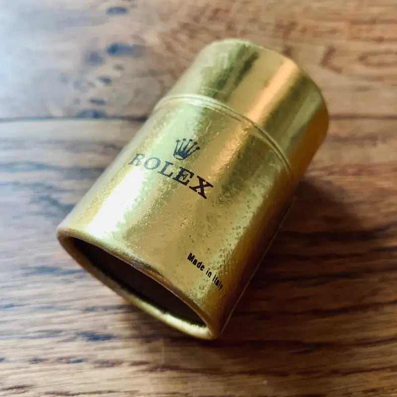 Contenitore o tappo cilindrico di colore oro a marchio Rolex.