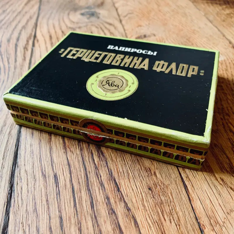 Scatola di sigarette russe etichettata ’Черноморна флор-’ su una superficie di legno.