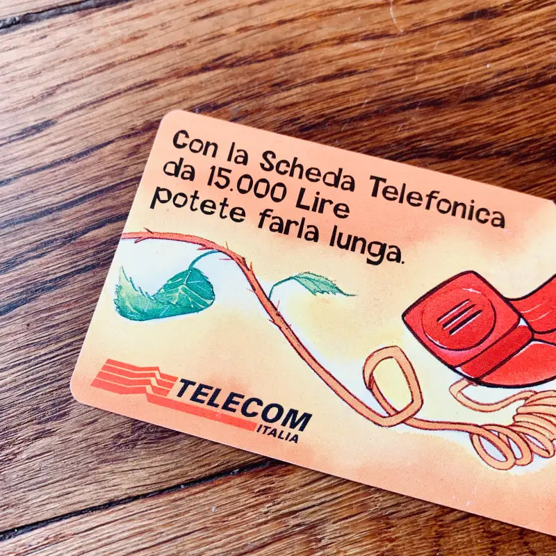 Scheda telefonica vintage di Telecom Italia con grafica e testo colorati.