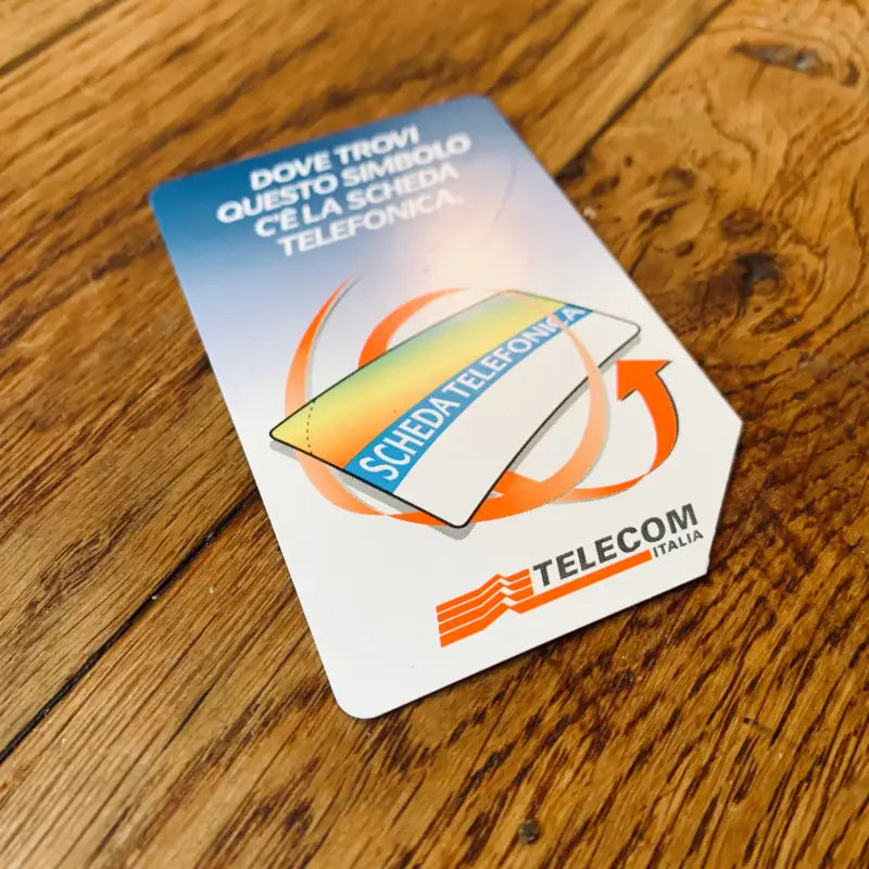 Scheda telefonica Telecom con logo colorato su superficie in legno.