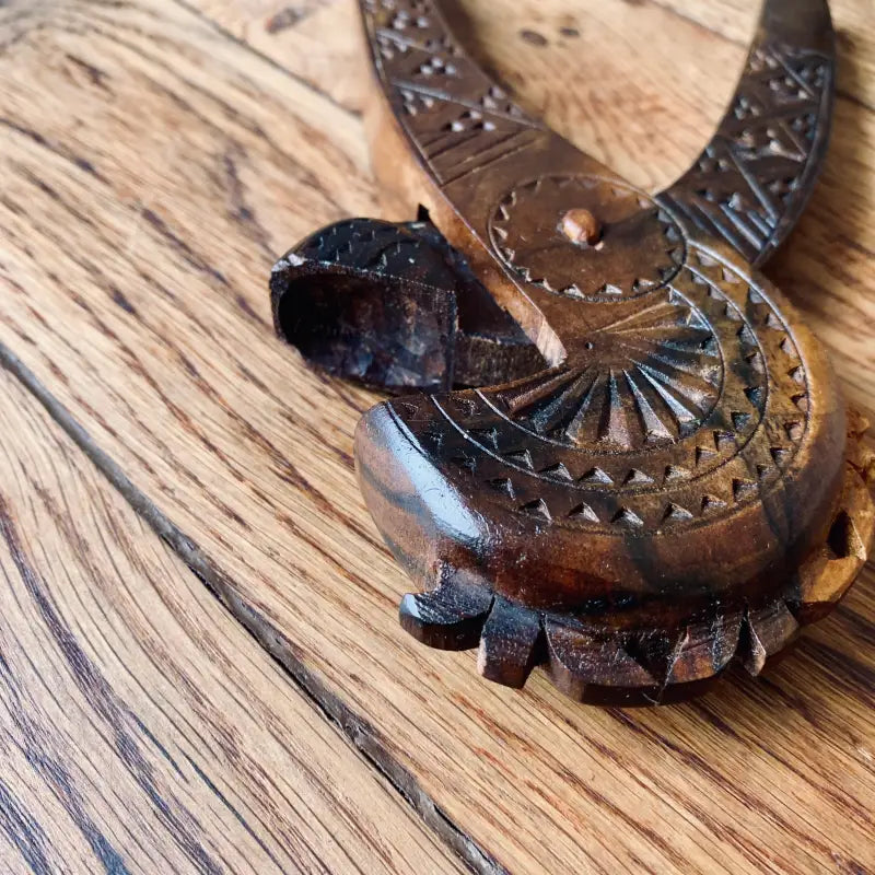 Geco o lucertola scolpita in legno con motivi intricati sul corpo.