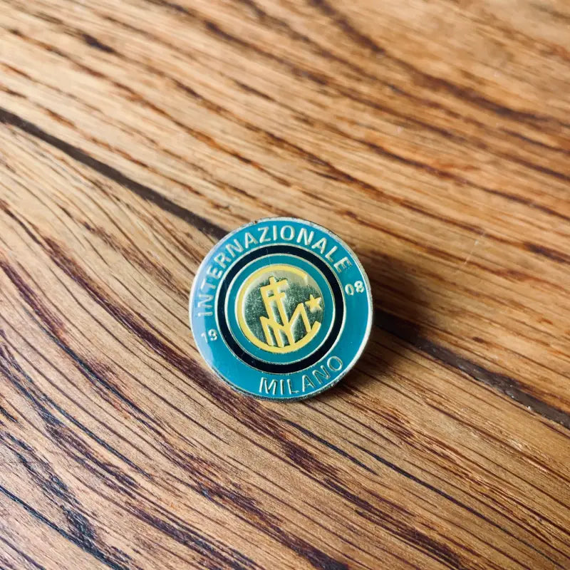 Distintivo circolare in smalto con il logo della squadra di calcio Inter Milan nei colori verde acqua e oro.
