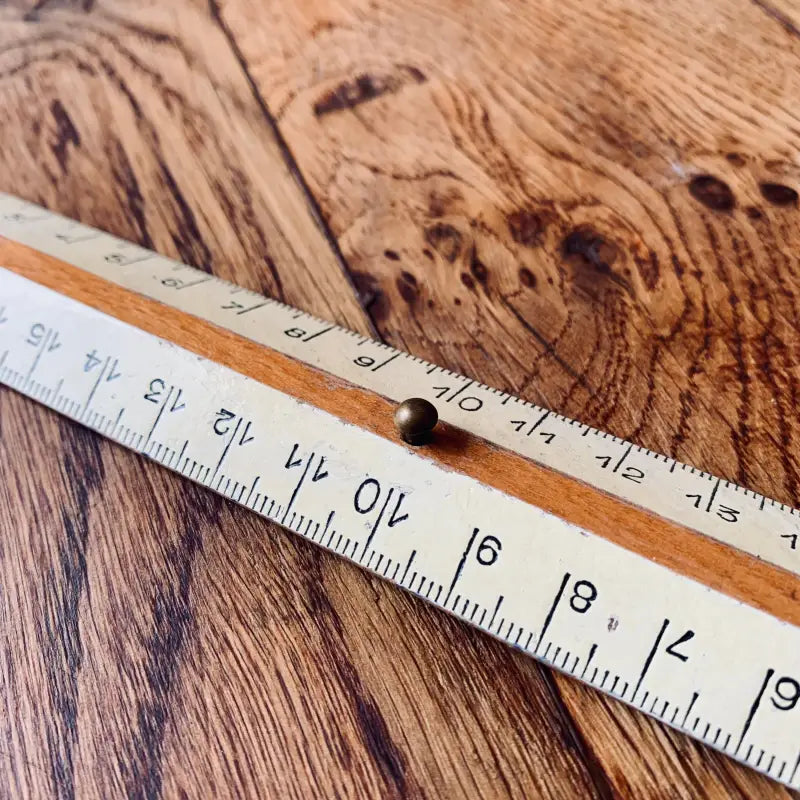 Righello pieghevole o regola da falegname con misure imperiali su una superficie di legno.