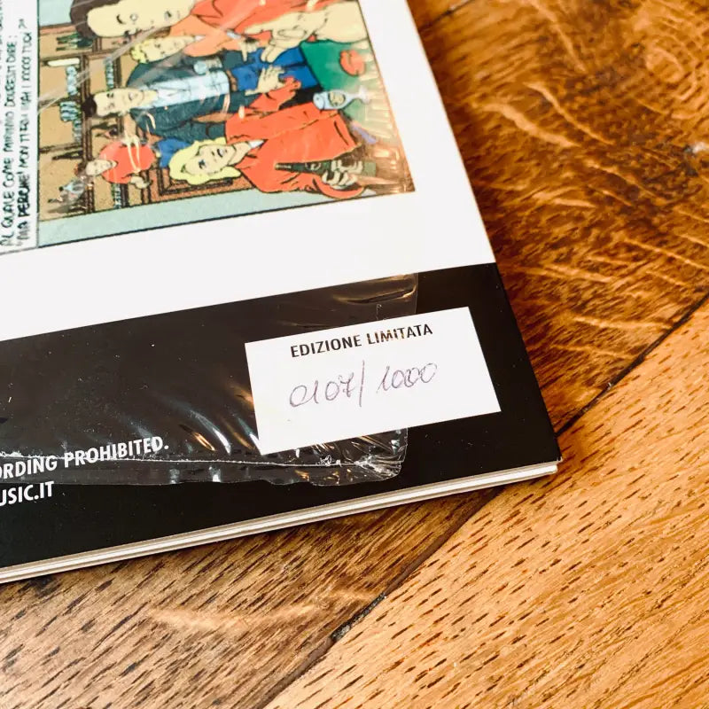 Libro o album con copertina illustrata a colori adagiato su una superficie di legno.