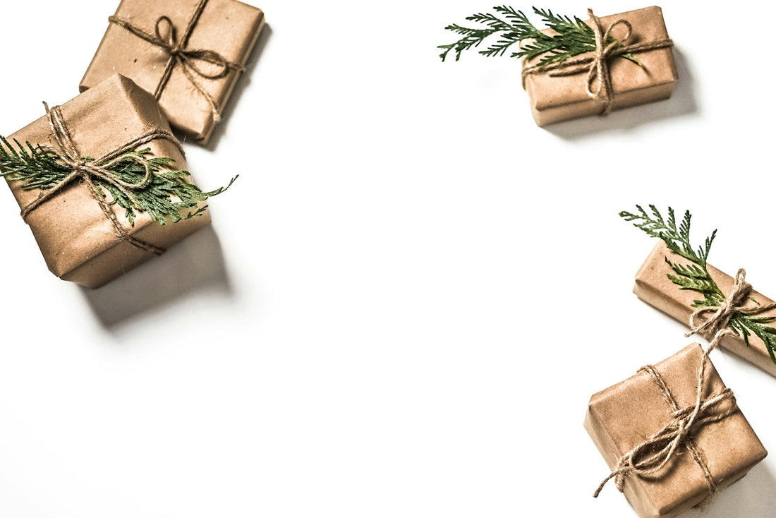 Regali di Natale incartati in carta avana su un tavolo chiaro
