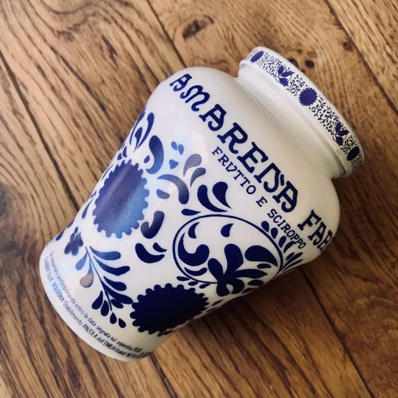 Vaso in ceramica decorato con motivi floreali blu, etichettato ’Rodarina Fine Foods’.
