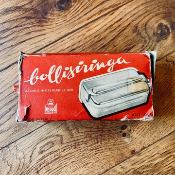 Scatola rossa d’epoca per un utensile da cucina in acciaio inossidabile chiamato ’bollisiringu’.