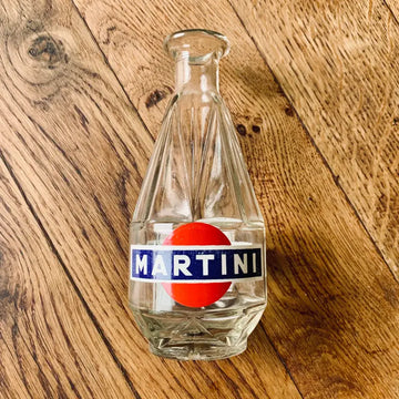 Bottiglia in vetro trasparente con logo Martini e disegno del cerchio rosso.