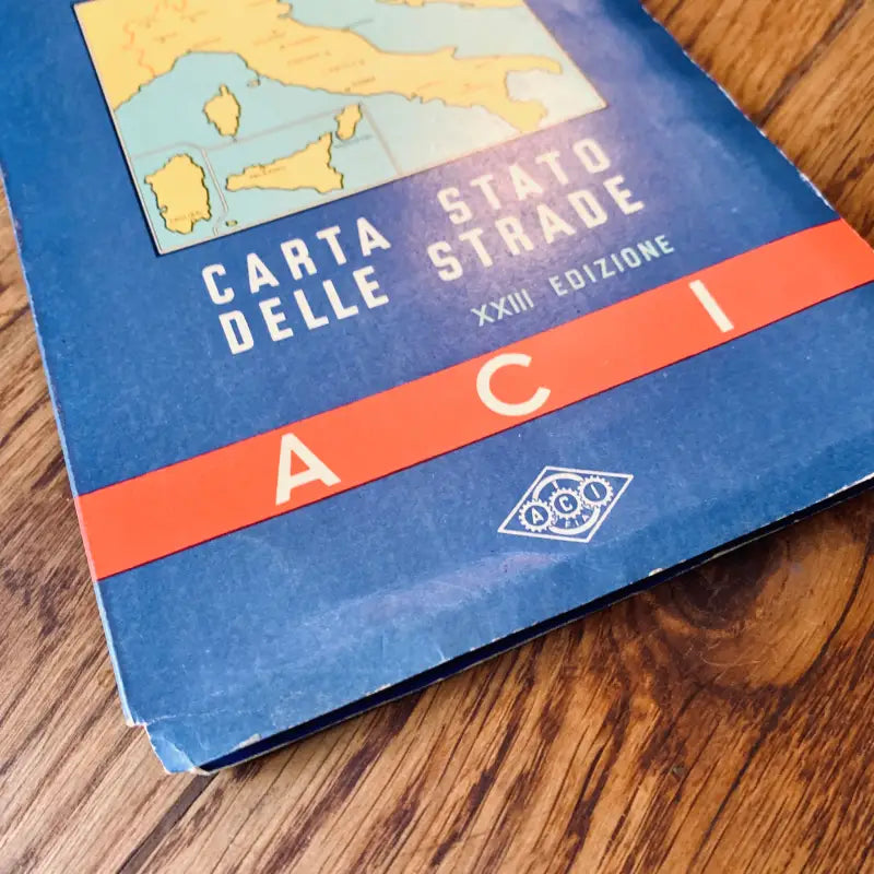 Libro di carte stradali italiane intitolato ’Carta Stato Delle Strade’ su una superficie di legno.