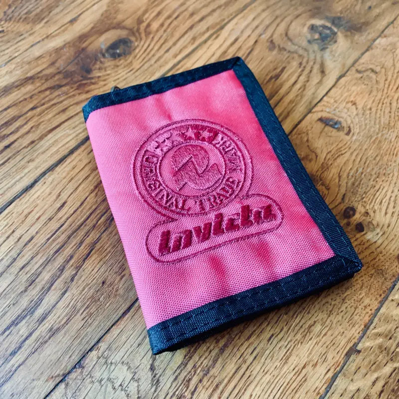 Portafoglio o portacarte rosa con logo ’Invicta’ ricamato ed emblema circolare.
