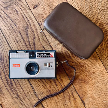 Macchina fotografica Kodak Instamatic d’epoca con cinturino da polso e custodia in pelle.