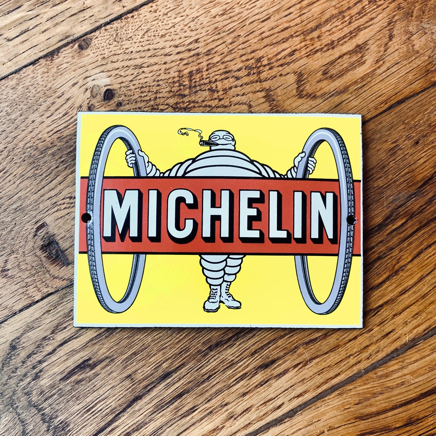 Insegna con logo Michelin in stile vintage con l’iconico personaggio dell’omino Michelin tra due pneumatici.