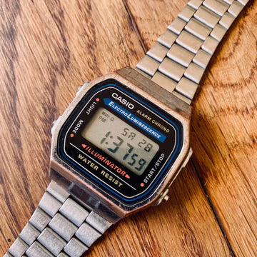 Classico orologio digitale Casio con cinturino in metallo su una superficie in legno.