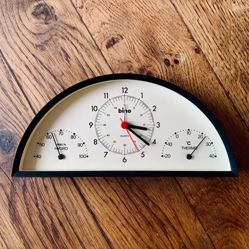 Orologio semicircolare con indicatori di umidità e temperatura integrati.