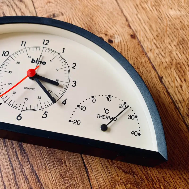 Orologio da parete con termometro integrato su una superficie in legno.