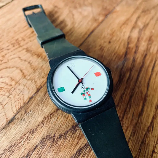 Orologio da polso con quadrante bianco minimalista con forme geometriche colorate al posto dei numeri.