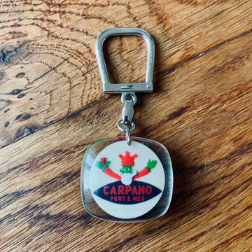 Portachiavi con logo del vermouth Carpano racchiuso in un ciondolo di plastica trasparente.