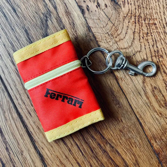 Portachiavi in tessuto rosso e giallo a marchio Ferrari con clip in metallo.