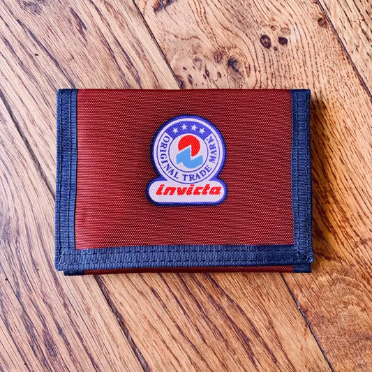 Portafoglio rosso con finiture blu e patch logo circolare.