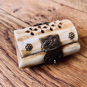Scatola decorativa in legno con chiusura in metallo e fori intagliati sulla parte superiore.